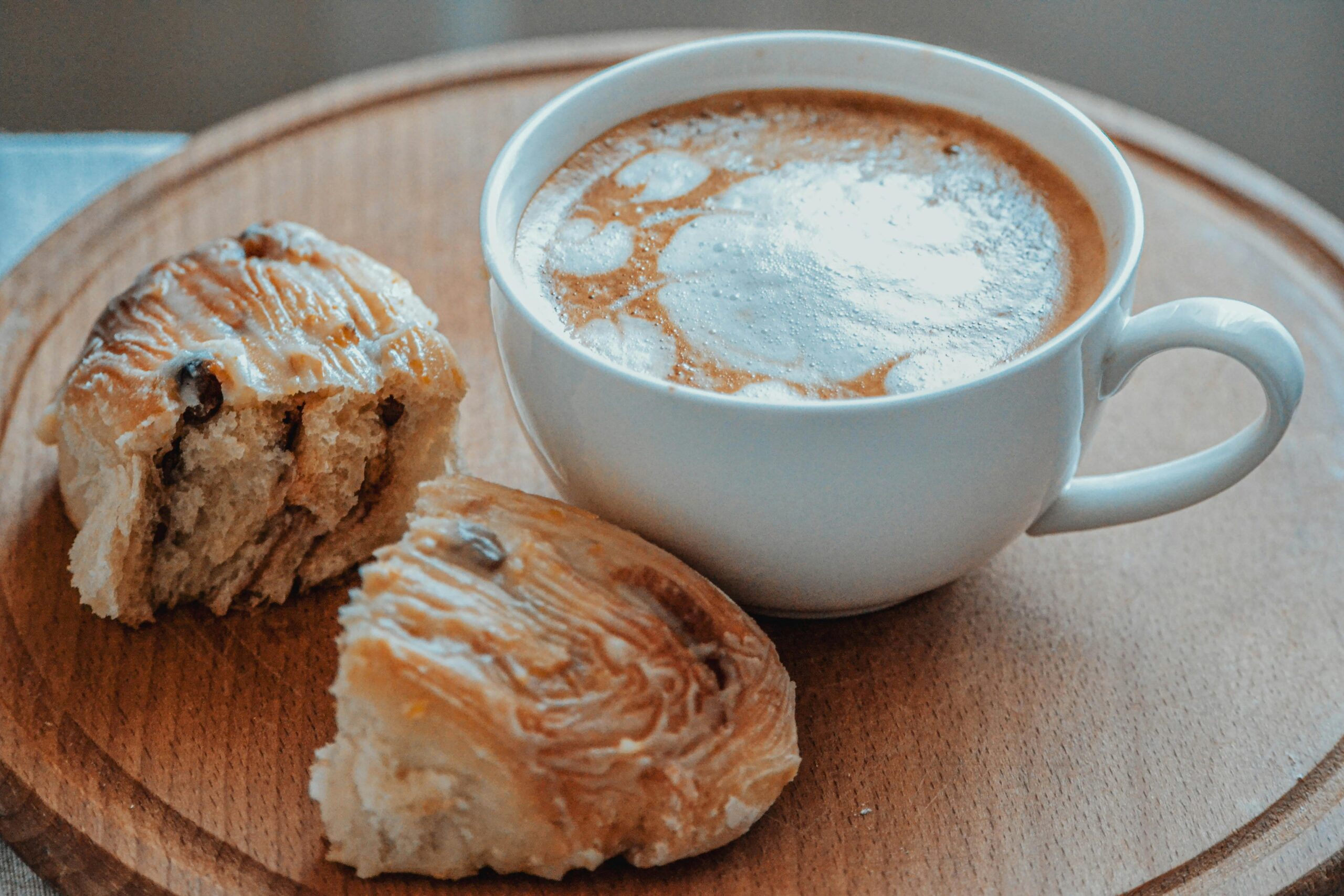 A warm cup of coffee paired with sweet cinnamon rolls on a wooden table.